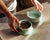 Two dog bowls, one has food and one has water and the owner hands are shown